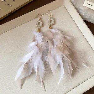 Exquisite close-up of bohemian style feather tassel earrings with natural stone detail.