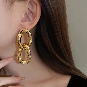 Close-up view of irregular gold metallic linked earrings worn by a model in detail