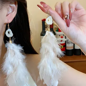 Close-up detail showing elegant long white feather tassel earrings with shiny golden hooks