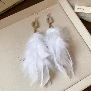 Detailed shot of white feather tassel earrings with elegant druzy stone accents
