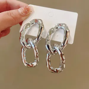Close-up of chunky silver irregular oval link earrings with hammered metal texture.