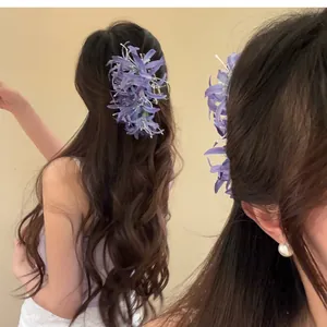 Gros plan d'une pince à cheveux lys araignée en tissu violet sur cheveux longs