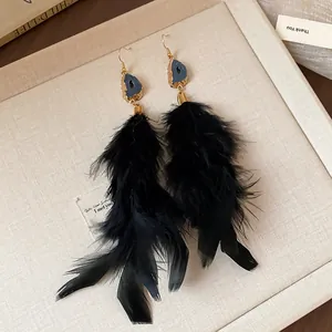 Detailed view of elegant long black feather tassel earrings with blue stone detail.