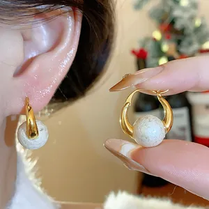 Close-up detail of 18k gold plated pearl hoop earrings in French retro style worn on ear.