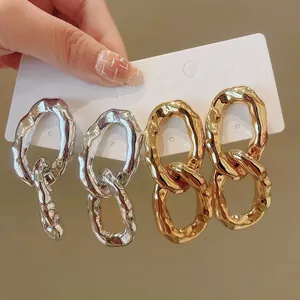 Detailed view of gold and silver chunky irregular textured oval metallic hoop earrings