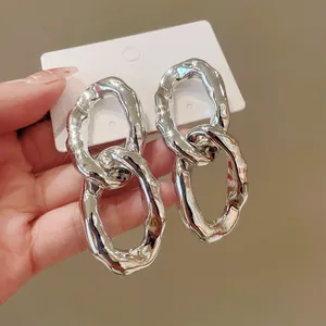 Close-up detail of chunky silver-toned irregular oval interlocking metal hoop earrings