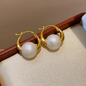 Macro detail of 18k gold plated hoop earrings featuring textured white pearls