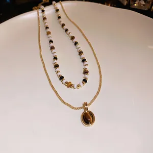 Dettaglio di una collana retrò a doppio strato con ciondolo occhio di tigre e perline