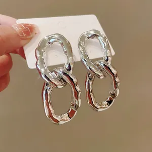 Close-up of silver irregular double oval link earrings with a glossy metallic finish.