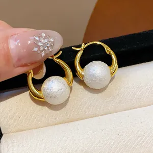 Detailed close-up view of elegant 18k gold plated hoop earrings with textured white pearls