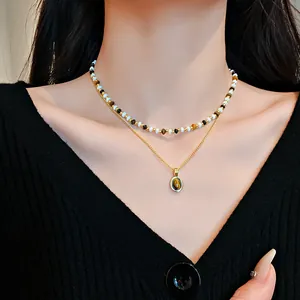 Primo piano di una collana a due strati con perle occhio di tigre e ciondolo in oro