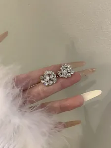 Detailed macro view of sparkling rhinestone-encrusted ear cuffs held on fingers.