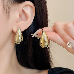 Nahaufnahme von goldenen Metall-Ohrringen in Tropfenform mit poliertem Finish.