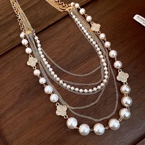Elegante mehrlagige Goldkette mit weißen Perlen und glitzernden Kleeblatt-Anhängern