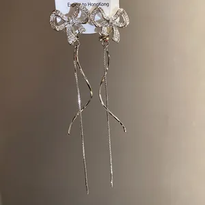 Detailansicht von silbernen Schleifenohrringen mit Zirkonia und eleganten Quasten