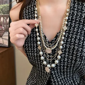 Detailansicht einer mehrlagigen Halskette mit Perlen und Goldkette an einem Modell.