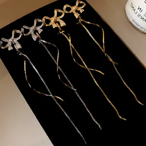 Nahaufnahme von eleganten Schleifen-Ohrclips mit Quasten in Gold und Silber