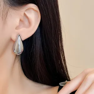 Detailaufnahme minimalistischer silberner Wassertropfen-Ohrstecker an einem weiblichen Modell