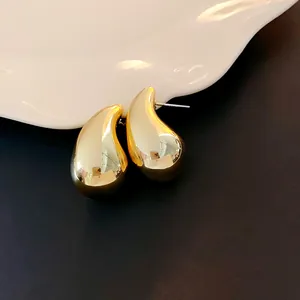 Makroansicht von glänzenden goldenen Tropfenohrsteckern mit metallischem Spiegelglanz