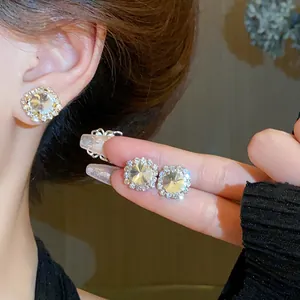 Close-up detail of luxury square crystal stud earrings with halo diamond setting