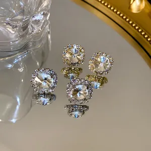 Close-up of sparkling round crystal stud earrings reflected on a luxury mirror surface.