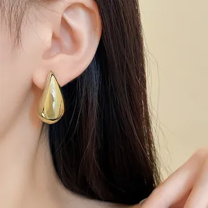 Detaillierte Nahaufnahme eines minimalistischen goldenen Tropfenohrrings am Ohr getragen
