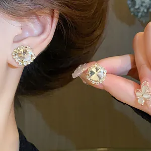 Close-up detail of round sparkling crystal stud earrings in a gold setting
