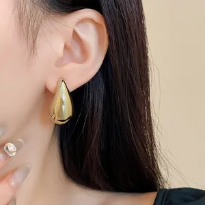 Nahaufnahme von minimalistischen goldenen Tropfenohrsteckern an einem Model für einen Look