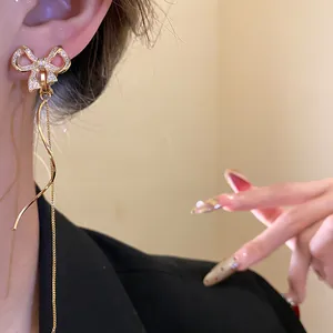 Nahaufnahme von eleganten 18k vergoldeten Zirkonia Schleifenohrringen mit Quasten