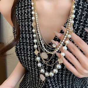Detailansicht einer luxuriösen mehrlagigen Goldkette mit eleganten Perlen und Kleeblättern