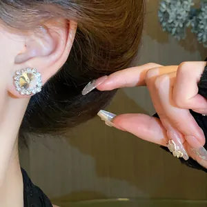 Close-up of a luxurious square rhinestone stud earring worn by an Asian model