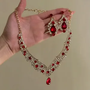 Detail view of gold-tone vintage necklace and earrings set with red teardrop stones