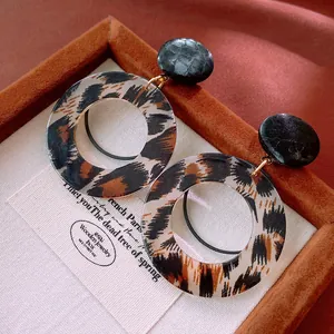 Vista de detalle de pendientes retro con estampado de leopardo y tachuelas negras texturizadas