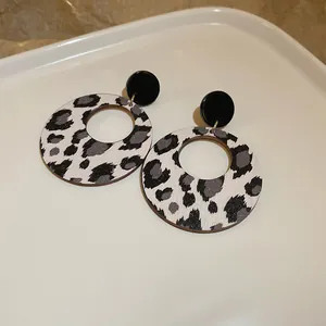 Vista detallada de pendientes circulares huecos con estampado de leopardo en bandeja de cerámica