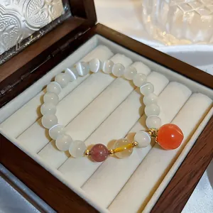 Elegant cat's eye stone beaded bracelet featuring a red peach charm in a wooden box