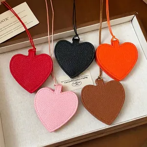 Five colorful heart-shaped leather pendant pouches for sunglasses displayed in a box