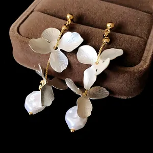 Close-up of elegant long tassel petal earrings with white baroque pearls in a gift box
