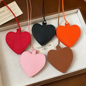 Detail of five colorful leather heart pendants in a white display tray