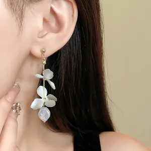 Close-up detail of elegant French style petal and pearl tassel drop earrings on model.