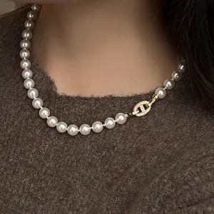 Dettaglio di una collana di perle vintage con chiusura a naso di maiale dorata e zirconi