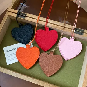 Detail showing five colorful leather heart pendants arranged in a wooden box