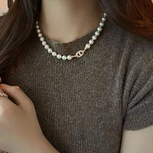 Primo piano di un'elegante collana di perle con chiusura ovale dorata vintage su una modella