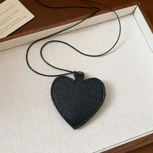 Close-up of black pebbled leather heart pendant sunglass holder on thin cord necklace