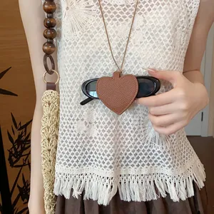 Close-up of a brown leather heart-shaped sunglasses holder pendant worn as a necklace