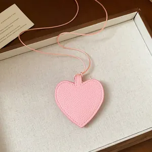 Detail view of a pink leather heart-shaped sunglasses storage pouch on a stylish thin cord.