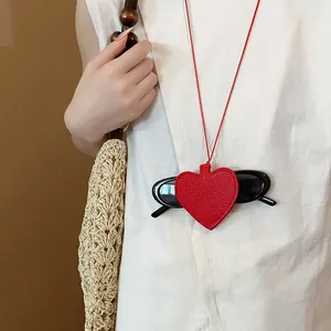 Red heart leather pendant used as a stylish sunglasses holder necklace on a model.