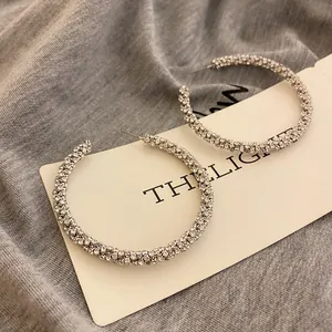 Detailed view of elegant rhinestone-encrusted hoop earrings on a minimal display card