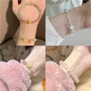 Detail showing handmade cat-eye stone beaded bracelets with rabbit and floral charms.