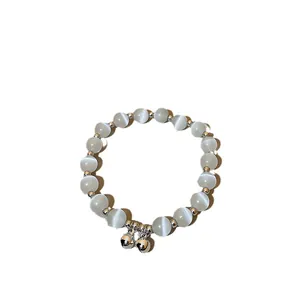 Elegant cat's eye beaded bracelet with silver bell charms on white background