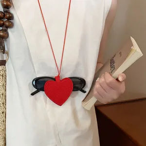 Close-up of a red leather heart-shaped pendant used as a stylish sunglasses holder necklace.
